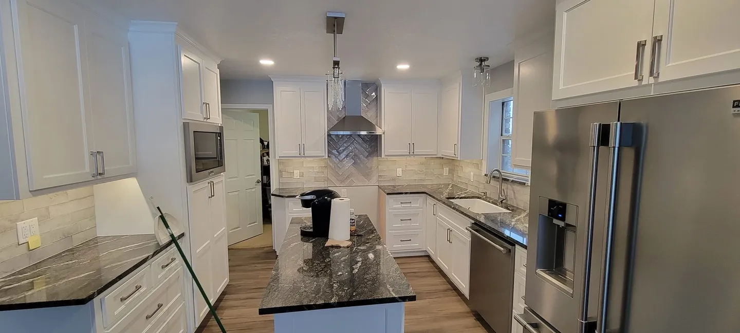 Modern kitchen with white cabinets and granite countertops.
