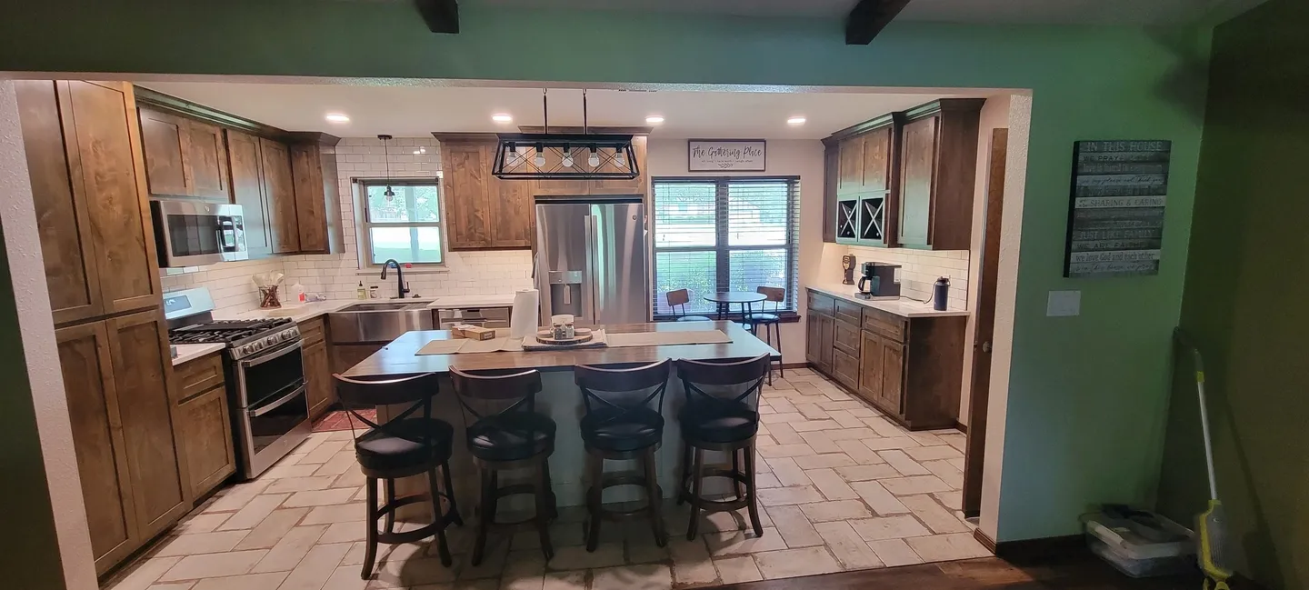 Modern kitchen with island, bar stools, and stainless steel appliances.