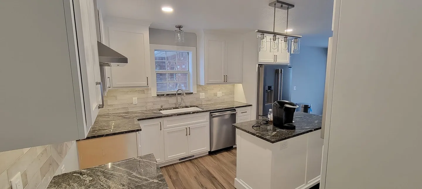 Modern kitchen with white cabinets and island counter.