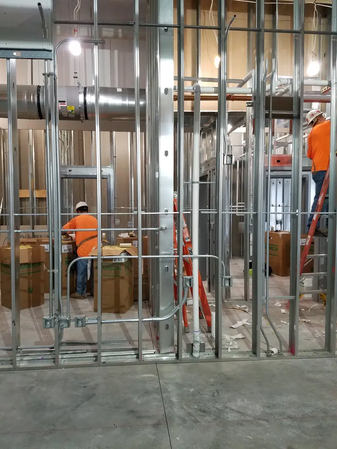 Construction workers assembling metal framing inside a building.